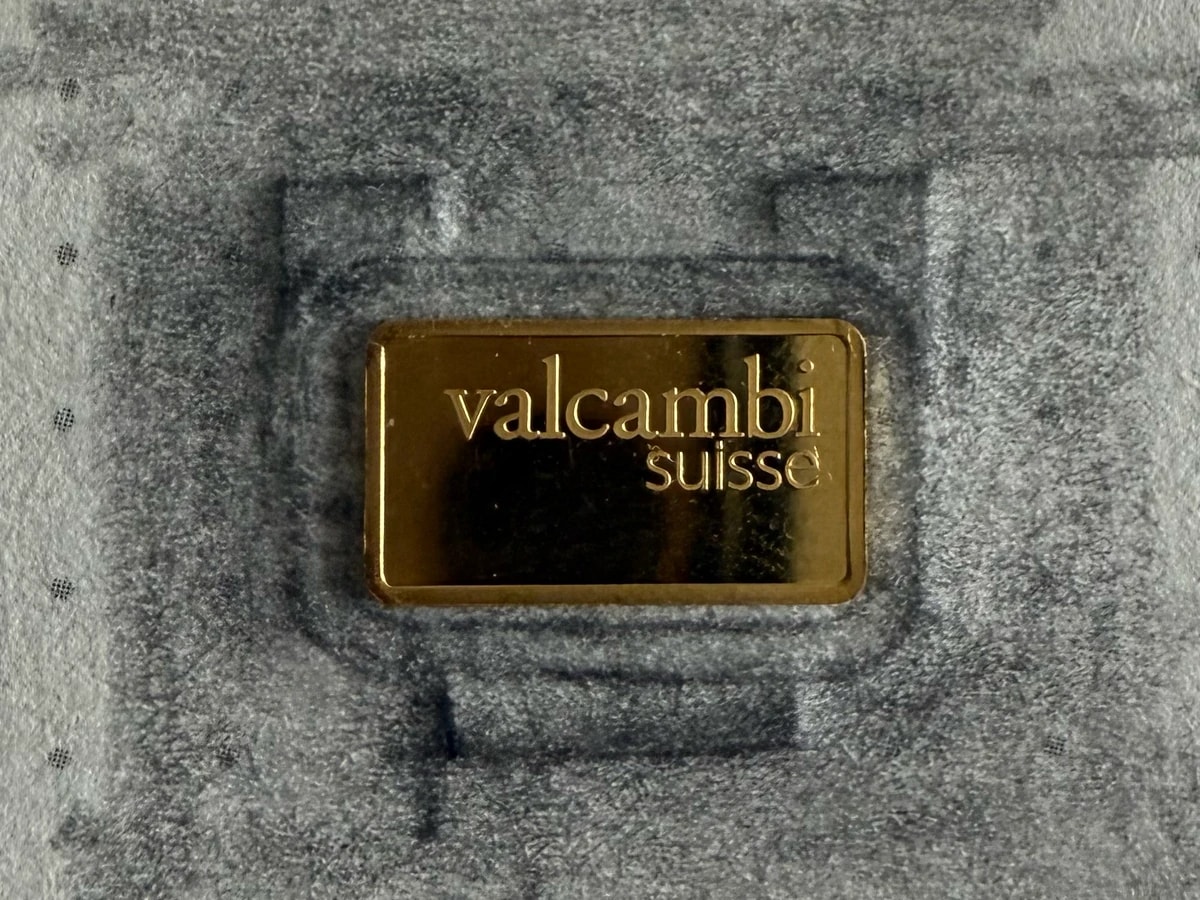 A one-gram gold bar lying on a pencil sketch of the first capsule